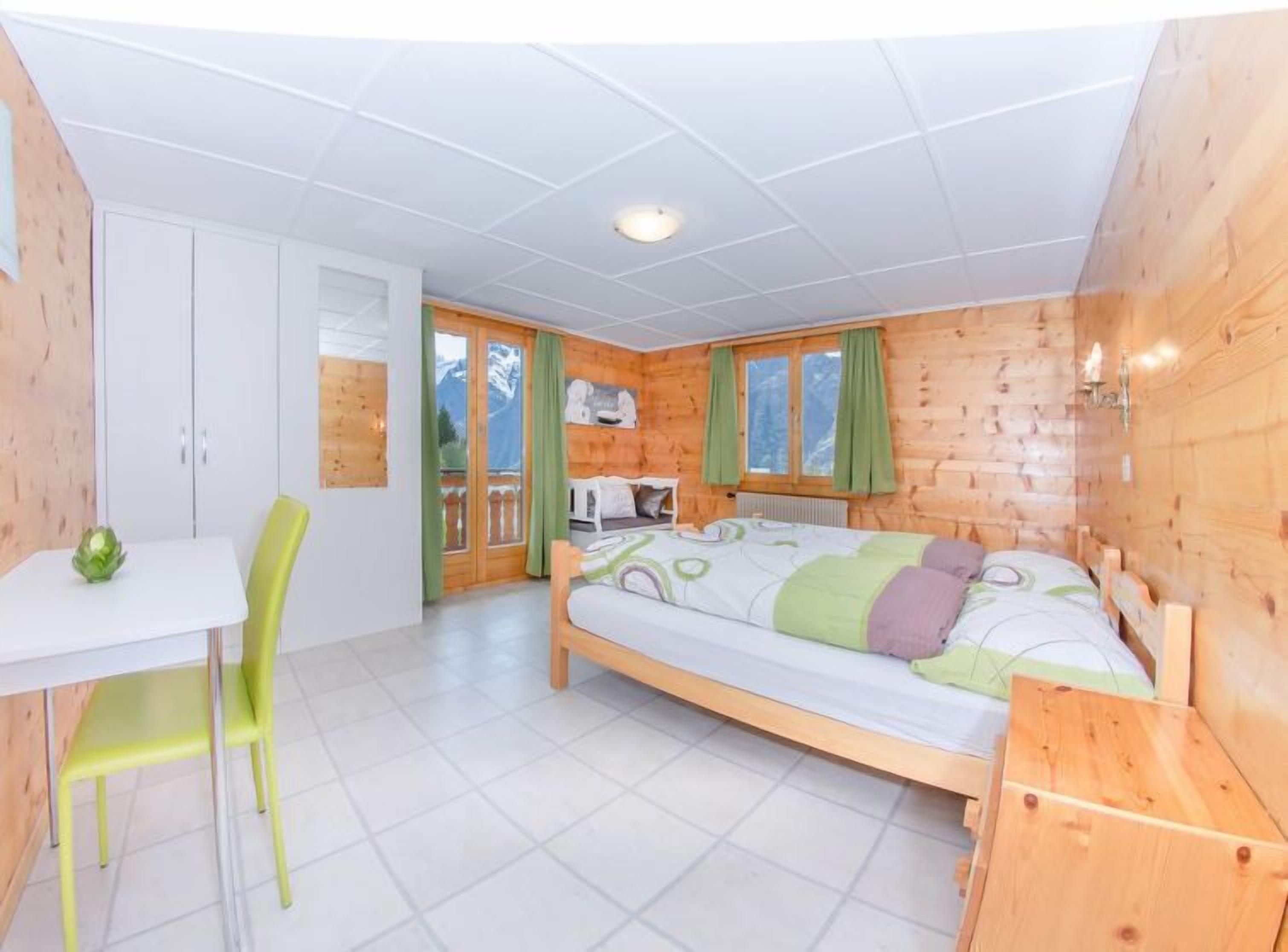 Ein Zimmer in einer Holzhütte mit einem Bett, einem kleinen Tisch und einem Stuhl.