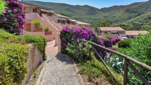 A hillside residential area with houses, a paved pathway, and lush greenery. - Terrazza Cala Rossa by Interhome (Nisporto)