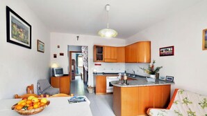 A compact living space with a kitchen, dining area, and a small seating area. - Terrazza Cala Rossa by Interhome (Nisporto)