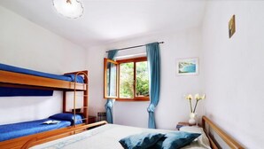 A room with bunk beds, a window with curtains, a bedside table with a lamp, and a painting on the wall. - Terrazza Cala Rossa by Interhome (Nisporto)