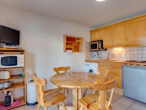 Une cuisine compacte dotée de meubles en bois, d’un four à micro-ondes, d’une machine à café et d’un lave-linge.
