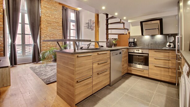 A modern kitchen with wooden cabinets, a dishwasher, an oven, and a coffee maker.