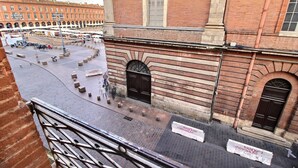 A courtyard with a paved area, a building with arched windows, and a sign that reads "toujours métropole".