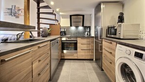 A modern kitchen with wooden cabinets, stainless steel appliances, and a built-in washing machine.