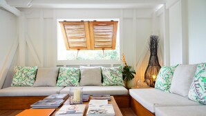 Un salón acogedor con un juego de sofá, una mesa de centro con libros y una ventana con contraventanas de madera.