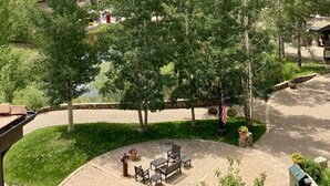 Un quartier résidentiel avec des maisons, une cour pavée aménagée avec du mobilier d’extérieur, et une chaîne de montagnes en arrière-plan.