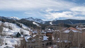 Une station de montagne avec des bâtiments de style chalet, des pistes de ski et des sommets enneigés.