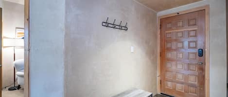 A hallway with a wooden bench, a coat rack, and a door with a keypad lock.