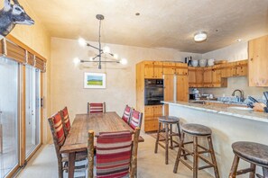 A kitchen with wooden cabinets, a central island with stools, and a ceiling light fixture.