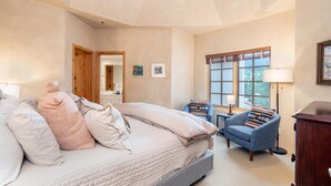 Une chambre à coucher avec un grand lit, une chaise, un bureau et une lampe.