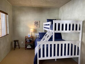 A bedroom with bunk beds, a bedside table with a lamp, and a wall art piece.