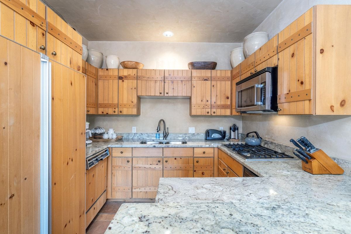 Een keuken met houten kastjes, een magnetron, een gasfornuis en een spoelbak.