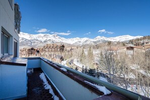 A balcony with a view of snow-covered mountains and a town below.