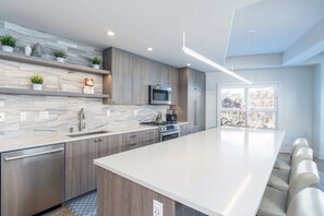 A modern kitchen with a large island, built-in appliances, and a view of the city through large windows.