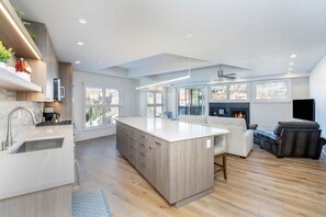 A modern kitchen with a large island, built-in appliances, and a fireplace.