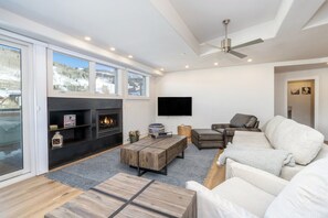 Ein modernes Wohnzimmer mit Kamin, Flachbildfernseher und einer Couch.