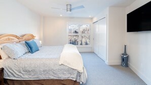 A bedroom with a bed, a ceiling fan, a window with a view, and a mounted TV. - Penthouse At The Peaks 751 (Mountain Village)