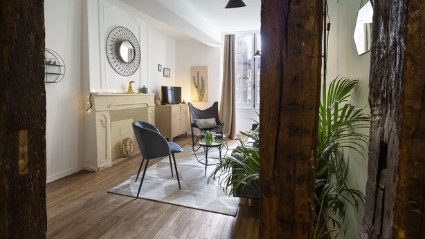 A cozy living room with a fireplace, a dining area with a table and chairs, and a large window with curtains. - LE TOUCAN, 2 pièces de charme et emplacement de rêve - Parlement de Bretagne (Rennes)
