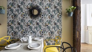 A dining area with a table set for four, a mirror, and a patterned wallpaper. - LE TOUCAN, 2 pièces de charme et emplacement de rêve - Parlement de Bretagne (Rennes)