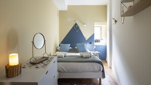 A bedroom with a bed, bedside table, lamp, and a wall-mounted mirror. - LE TOUCAN, 2 pièces de charme et emplacement de rêve - Parlement de Bretagne (Rennes)