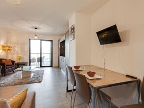 A modern living room with a sofa, coffee table, and a dining area with a table and chairs.
