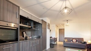 Una cocina moderna con electrodomésticos integrados, un comedor con mesa y sillas, y una sala de estar con sofá y mesa de centro.