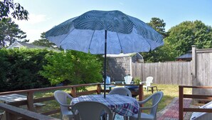 Une terrasse avec une table et des chaises, un parasol et une plateforme en bois.