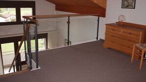 Une pièce avec un escalier en bois, une fenêtre à cadre blanc, une commode en bois et un tableau encadré accroché au mur.