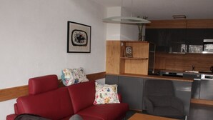 Un salon moderne avec un canapé rouge, un fauteuil gris et une table basse en bois. Un chat est sur le canapé.