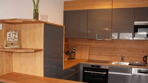 Une cuisine moderne avec des meubles en bois, des appareils électroménagers en acier inoxydable et un four encastré.