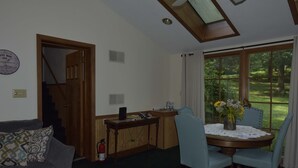 A dining area with a round table, four chairs, and a vase with flowers. There is a staircase leading to another room. - River Front Vacation Rental Property On The Clarion River in Clarington, Pa    (Clarington)