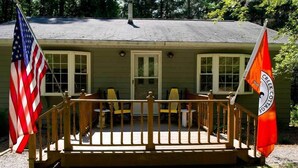 A house with a porch, two American flags, and a Creek Cottage flag. - River Front Vacation Rental Property On The Clarion River in Clarington, Pa    (Clarington)