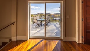 A wooden deck with a table and chairs, a view of a landscape, and a door leading to the deck. - The Sanctuary (Near Tecumseh) (Kingston)