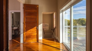 A hallway with wooden flooring leading to a door, a sign for Ethel Methodist Church, and a view of a deck with a railing. - The Sanctuary (Near Tecumseh) (Kingston)