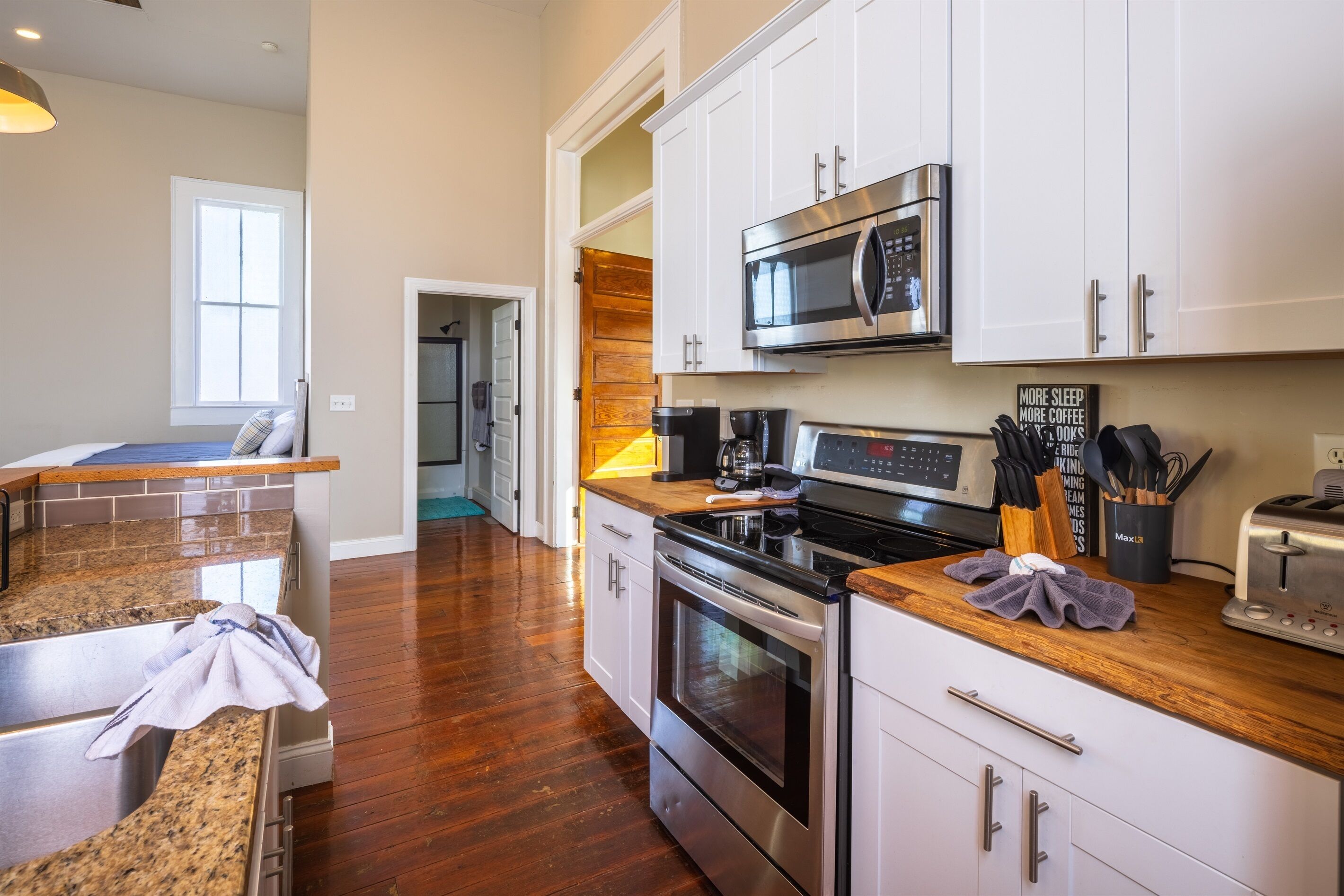 A modern kitchen with granite countertops, stainless steel appliances, and white cabinetry.