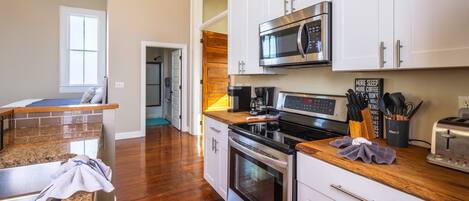 A modern kitchen with granite countertops, stainless steel appliances, and white cabinetry.
