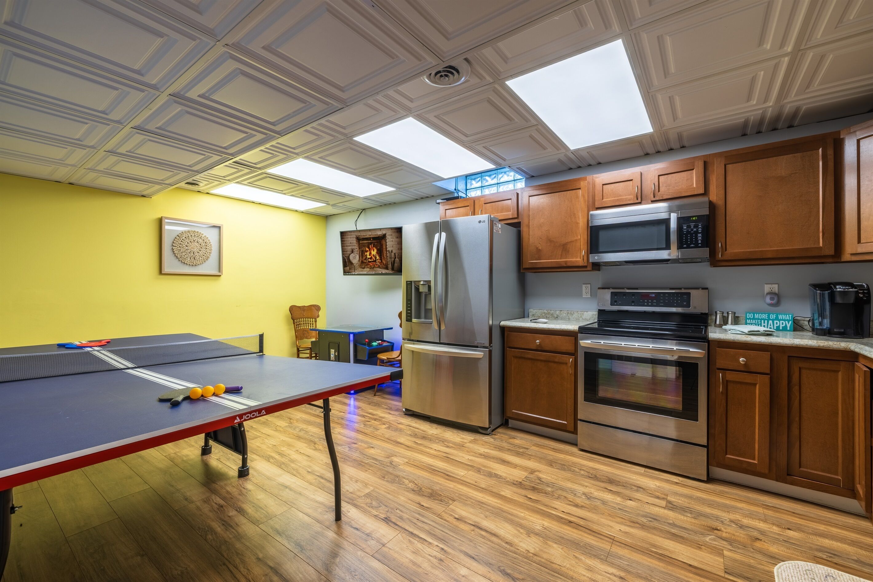 A kitchen with wooden cabinets, stainless steel appliances, and a ping pong table.