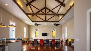 A spacious dining area with a high ceiling, wooden beams, and two large windows with stained glass. - The Sanctuary (Near Tecumseh) (Kingston)