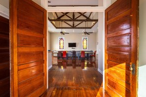 A wooden door leading to a room with a ceiling fan, a television, and a seating area with chairs and a table. - The Sanctuary (Near Tecumseh) (Kingston)