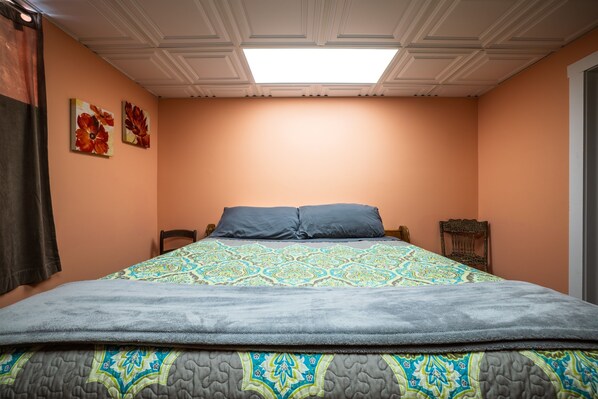 A bedroom with a large bed, a ceiling light, and two wall-mounted paintings. - The Sanctuary (Near Tecumseh) (Kingston)