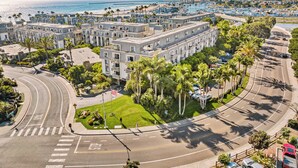A multi-story hotel with a central courtyard, surrounded by palm trees and a view of the beach. - A19 Lower Strand Cottage,10 secs to sand! Convenient location - corner of main rds (Oceanside)