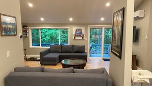 Un salon moderne avec un canapé d’angle, une table basse et une vue sur une terrasse dotée d’une balustrade.