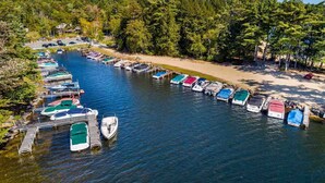 Un port de plaisance où des bateaux sont amarrés le long d’un canal étroit, entouré d’une forêt dense et sous un ciel dégagé.