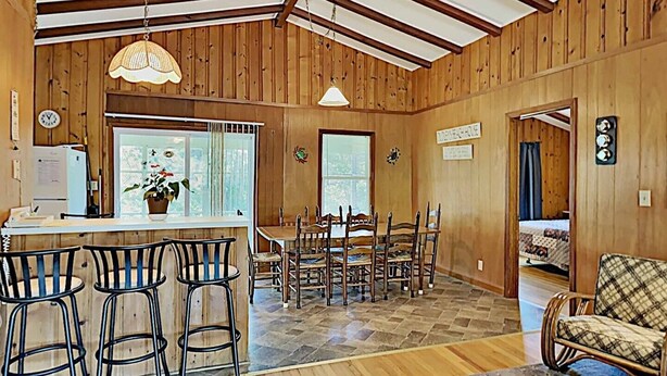 Un interior de madera con comedor, taburetes de bar y zona de estar.