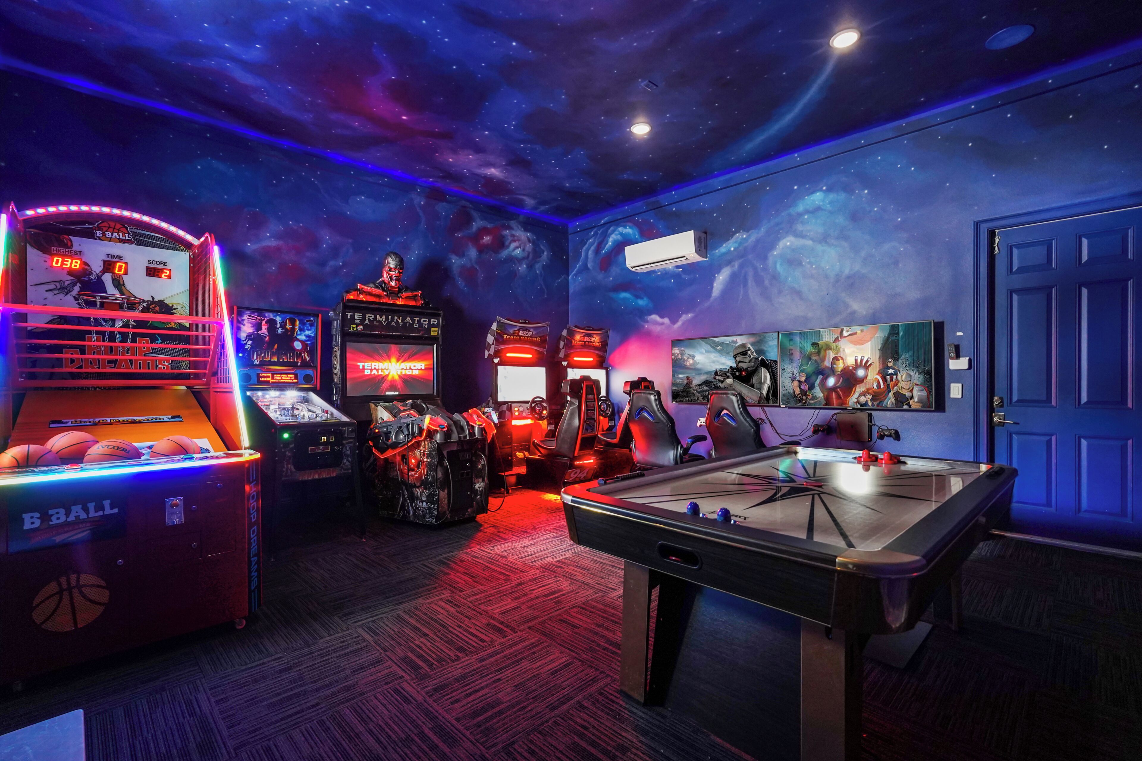 A room with a pool table, arcade games, and a TV screen displaying a game.