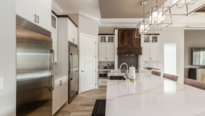 A modern kitchen with stainless steel appliances, white cabinetry, and a large island with seating. - Reunion Fantasy | Games Room, Secret Playroom, English Pub Bar (Kissimmee)