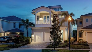 A two-story house with a covered front porch, a garage, and a well-maintained lawn. - Reunion Fantasy | Games Room, Secret Playroom, English Pub Bar (Kissimmee)
