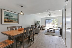 Cozy living area with a dining table for four, a large painting, and a sliding glass door leading to an outdoor space.