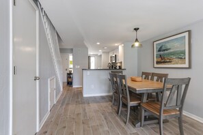Une cuisine moderne dotée d’un îlot central, d’un coin repas avec des chaises en bois et d’un escalier menant à un autre niveau.