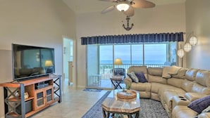 A living room with a television, leather sofa, and a balcony with a view. - NEW !  Ocean Front Paradise  @  South Beach Condos with Amazing Views !  (Flagler Beach)